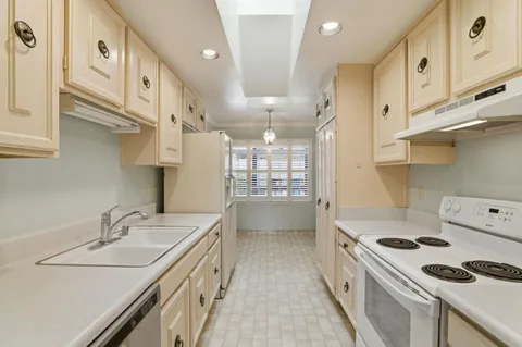a kitchen with granite countertop a sink a stove and a refrigerator