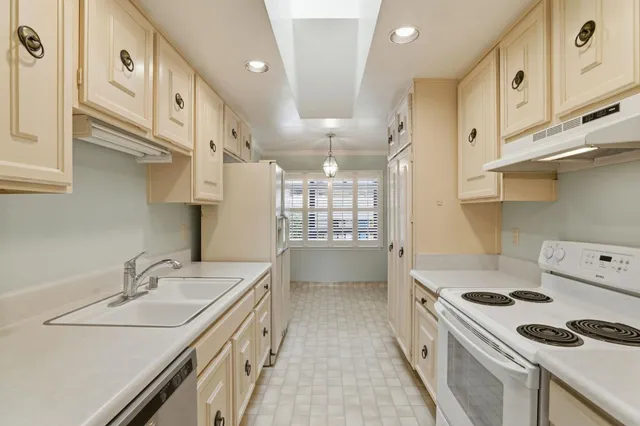 a kitchen with granite countertop a sink a stove and a refrigerator
