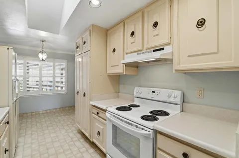 a kitchen with white cabinets and window