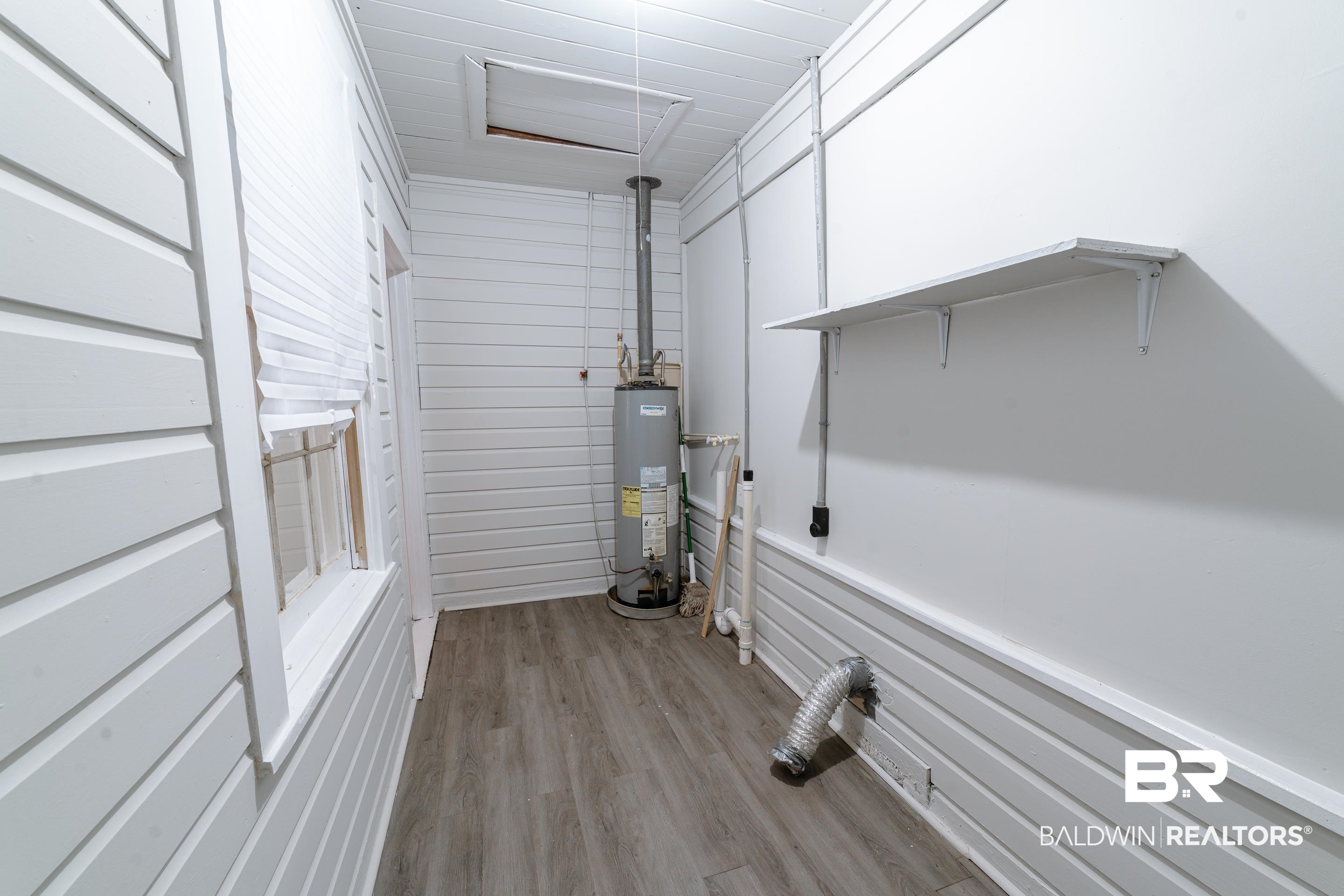 312 1st Street Mobile, AL 36611 - Photo 23 of 29 Laundry room with gas water heater, light hardwood / wood-style flooring, and wooden walls