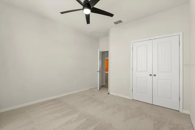an empty room with a ceiling fan and carpet