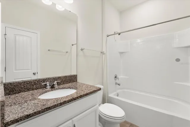a bathroom with a granite countertop sink a toilet and shower