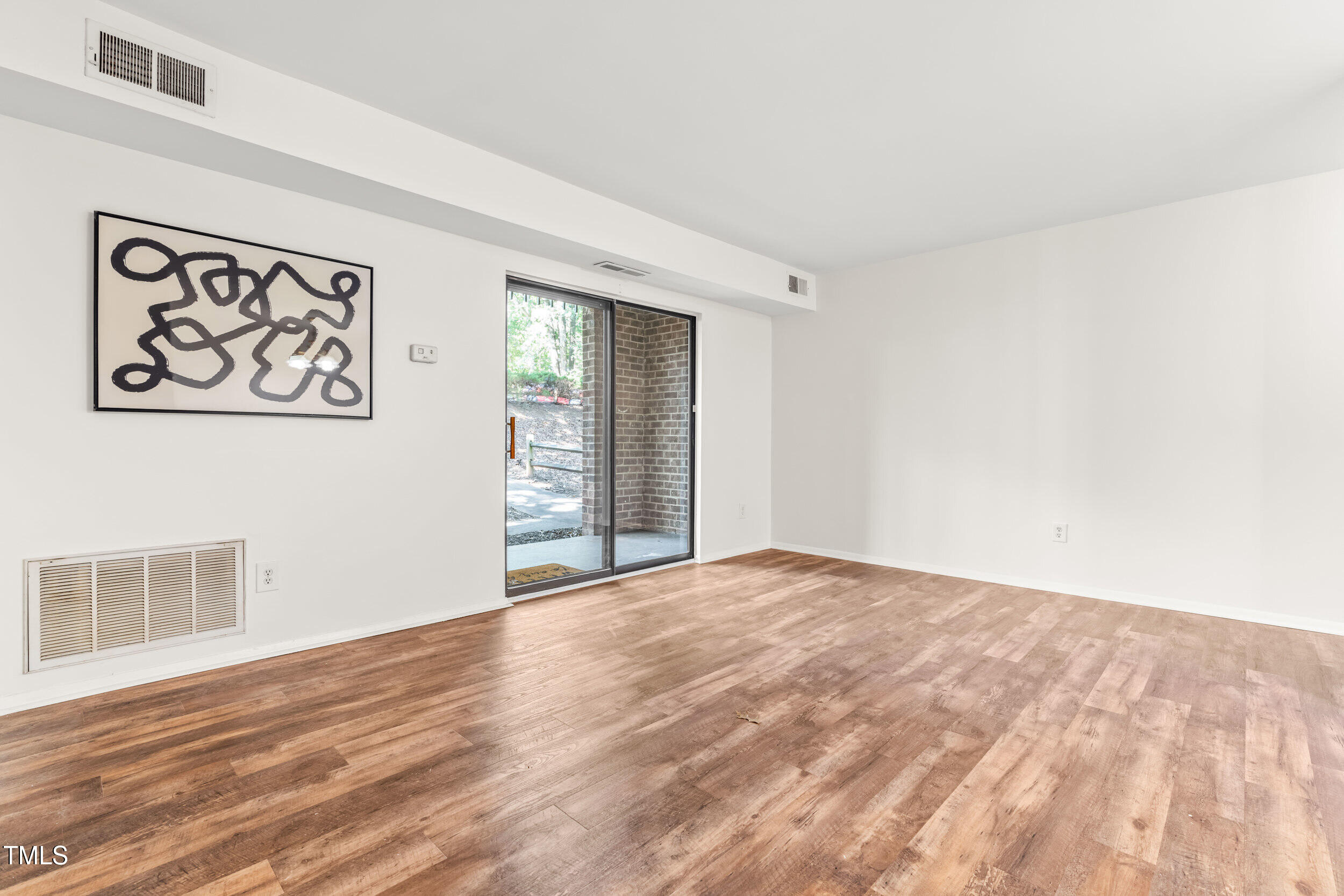 1212 Schaub Drive, Unit C Raleigh, NC 27606 - Photo 12 of 23 a view of an empty room with wooden floor and a window