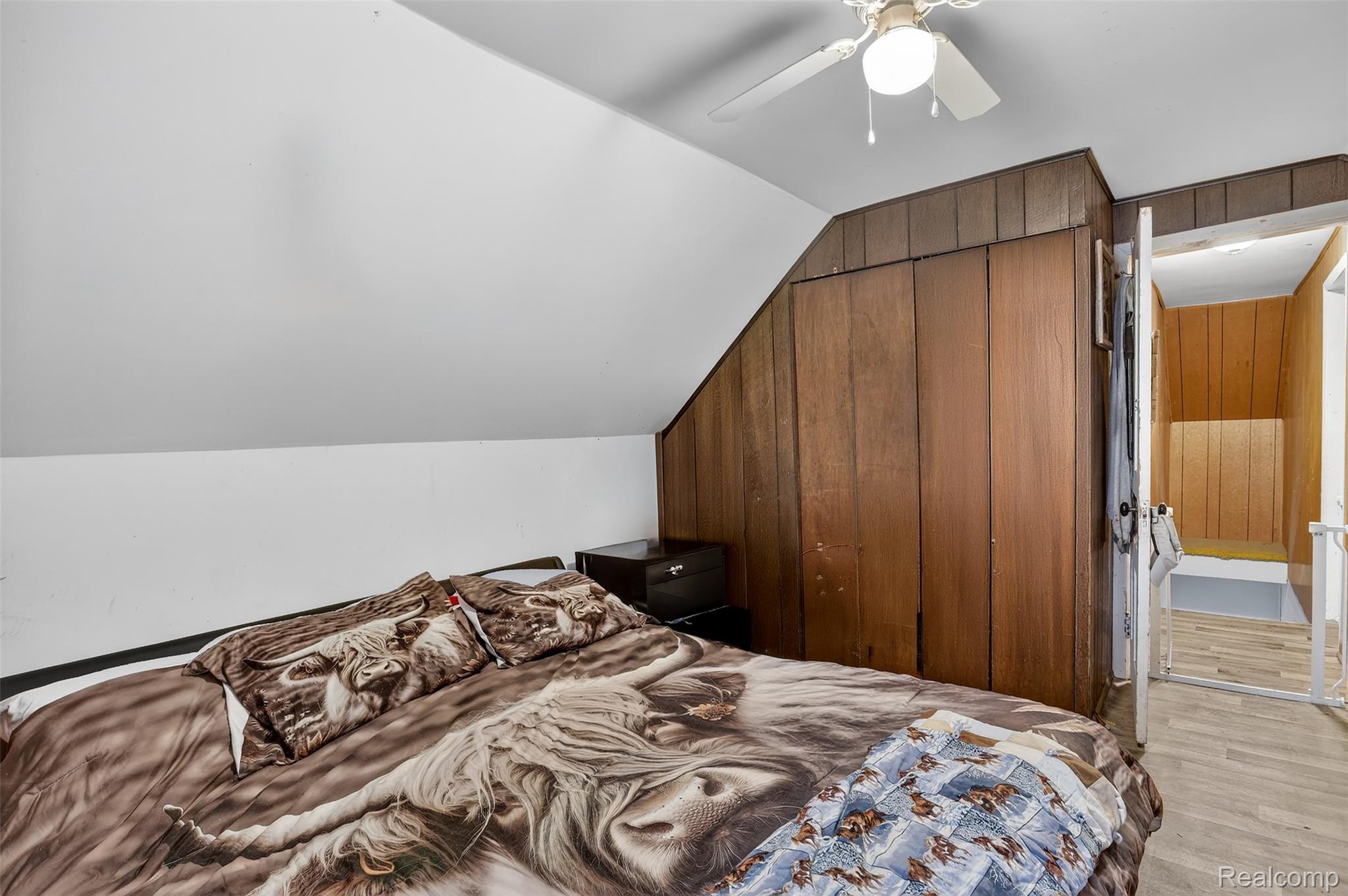 5639 Swaffer Road Millington, MI 48746 - Photo 22 of 25 Bedroom with lofted ceiling, a closet, wood walls, ceiling fan, and light wood-type flooring
