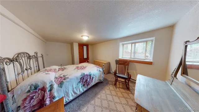 a bedroom with a bed next to a window with kitchen view