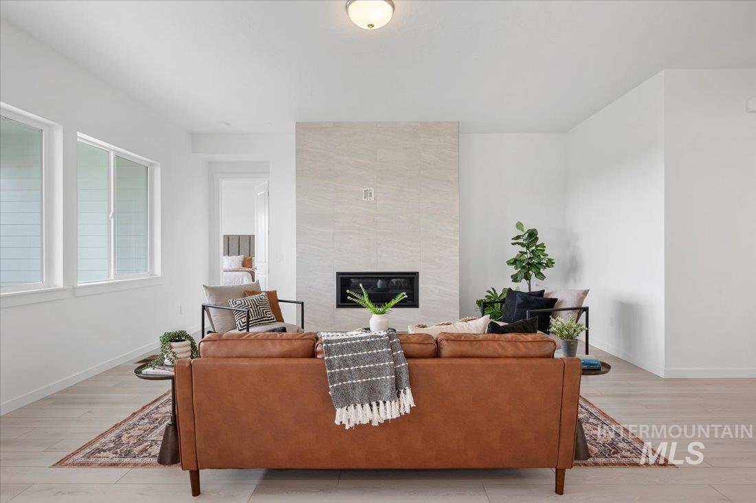 1120 West Switchgrass Drive Meridian, ID 83642 - Photo 2 of 13 Living area with a tiled fireplace and light wood-style flooring