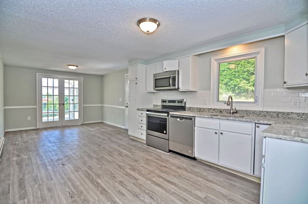 138 Leland Hill Road Sutton, MA 01590 - Photo 11 of 26 a kitchen with granite countertop wooden floors a stove a sink and a window