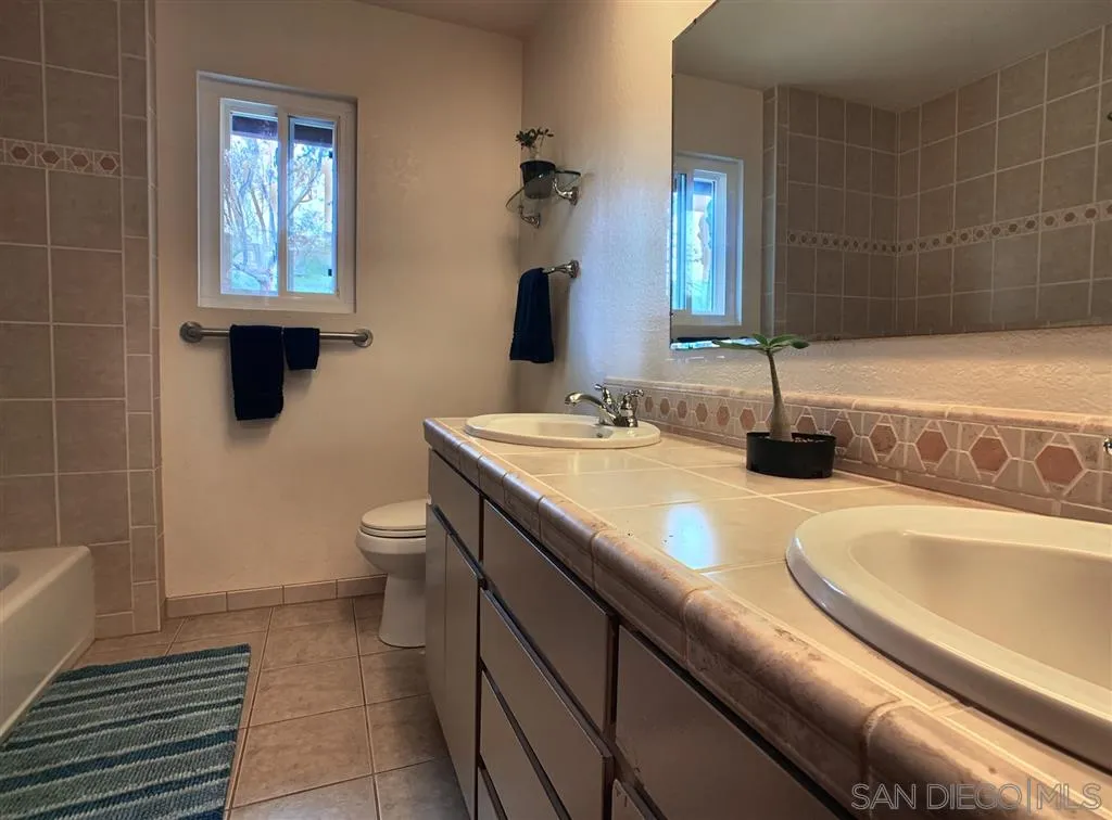 21152 Sutherland Dam Road Ramona, CA 92065 - Photo 18 of 25 a bathroom with a granite countertop sink a toilet and mirror