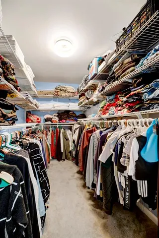 a view of walk in closet with clothes and shoes