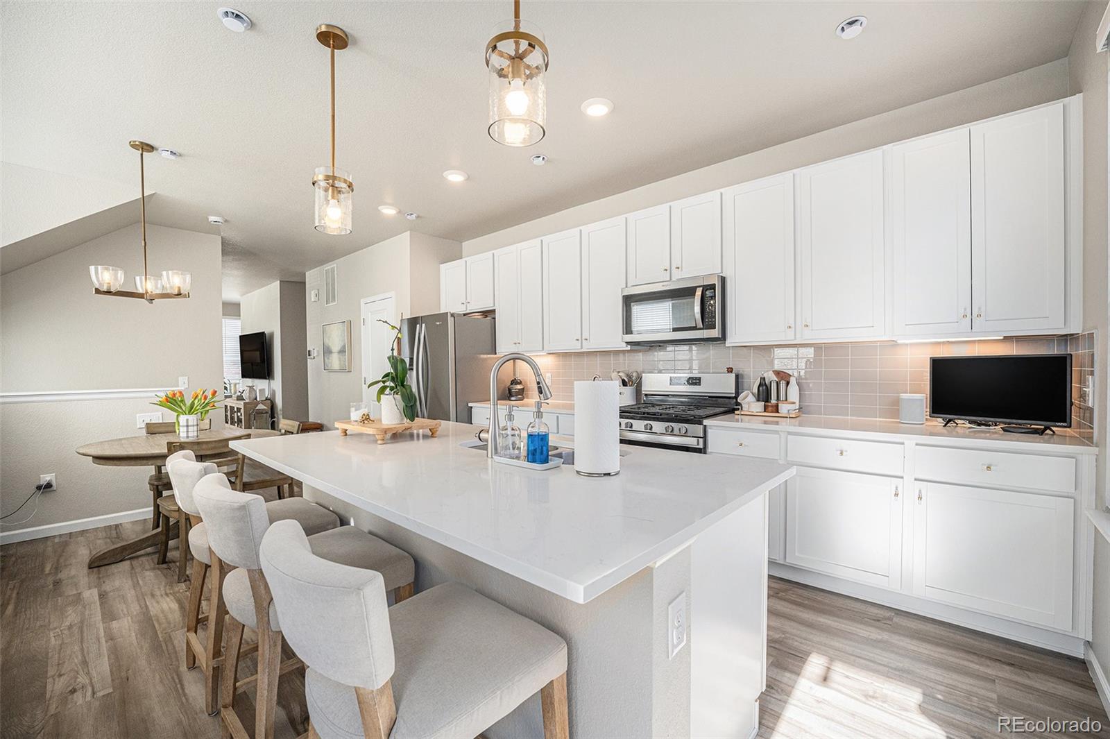 8430 Donati Terrace, Unit A Highlands Ranch, CO 80129 - Photo 4 of 26 a kitchen with a dining table chairs microwave and refrigerator