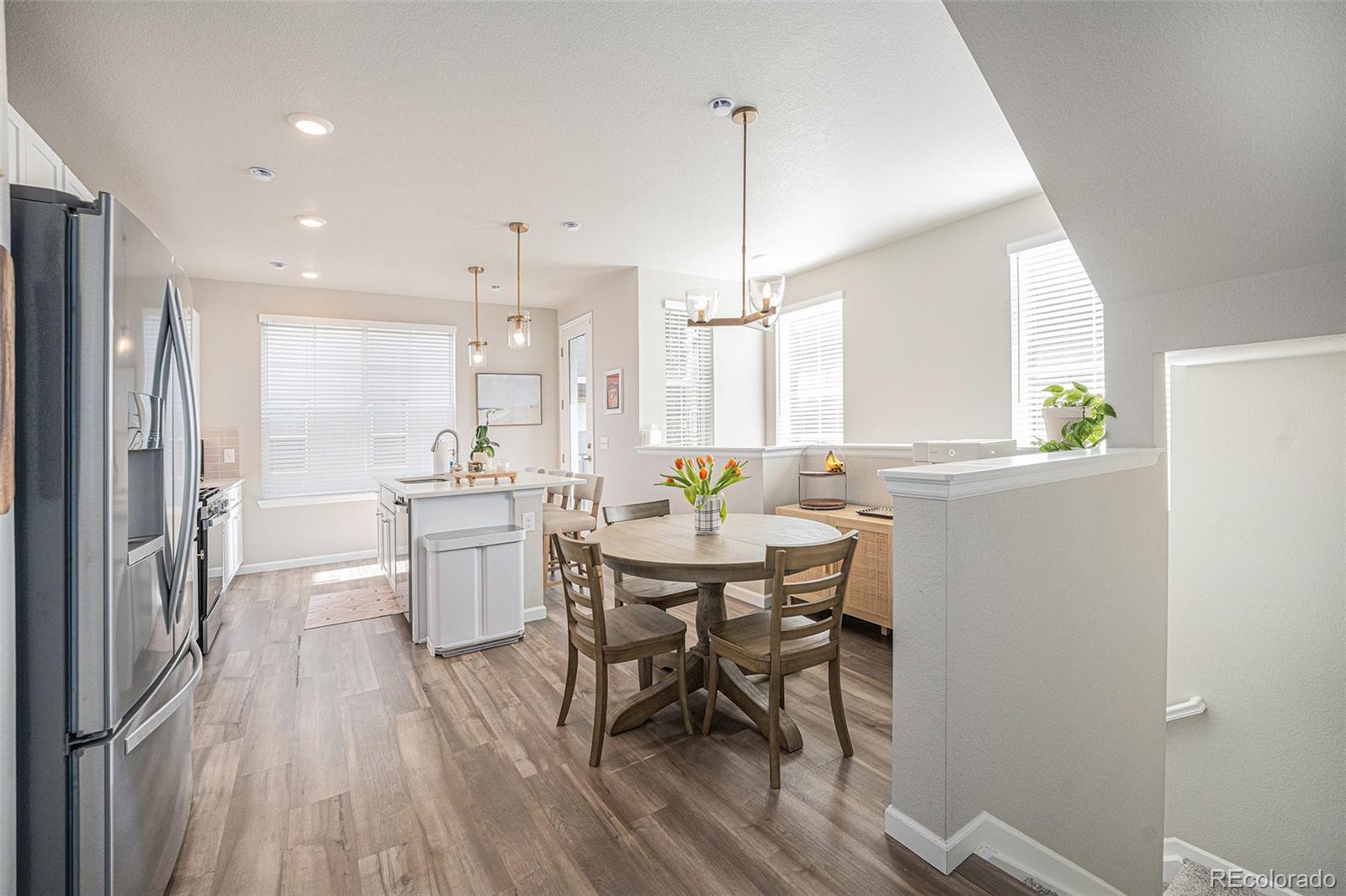 8430 Donati Terrace, Unit A Highlands Ranch, CO 80129 - Photo 5 of 26 a kitchen with stainless steel appliances a dining table chairs a sink and white cabinets