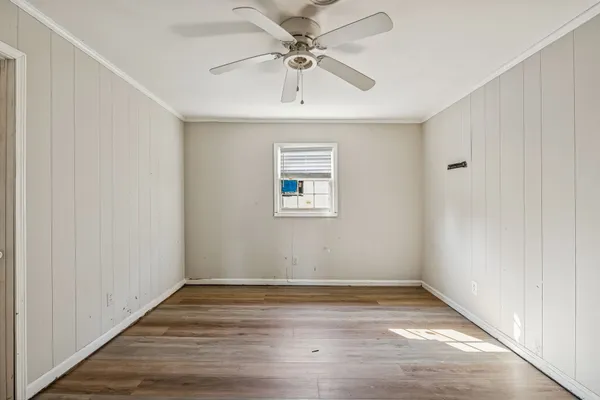 a view of an empty room with a window and wooden floor