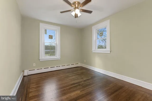 a view of an empty room with window and wooden floor