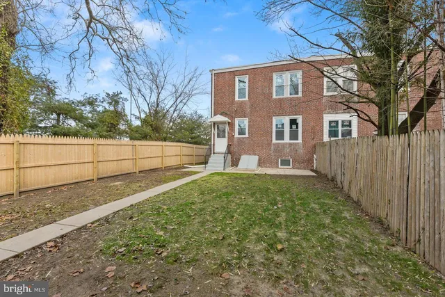 a brick house with a yard and large trees