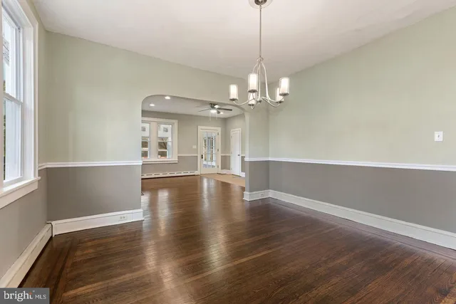 a view of a livingroom with wooden floor a ceiling fan and windows