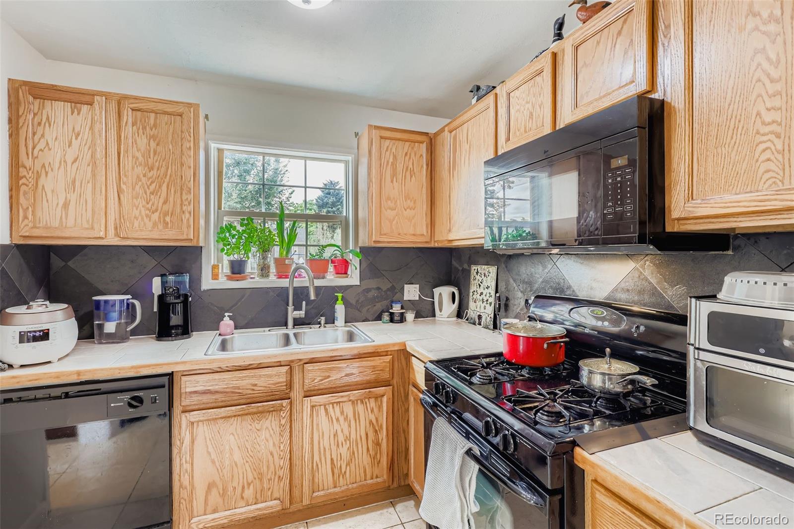 452 Perry Street Denver, CO 80204 - Photo 12 of 29 a kitchen with stainless steel appliances granite countertop a sink stove cabinets and a window