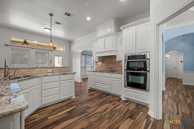 a kitchen with stainless steel appliances kitchen island granite countertop a stove a sink and a refrigerator