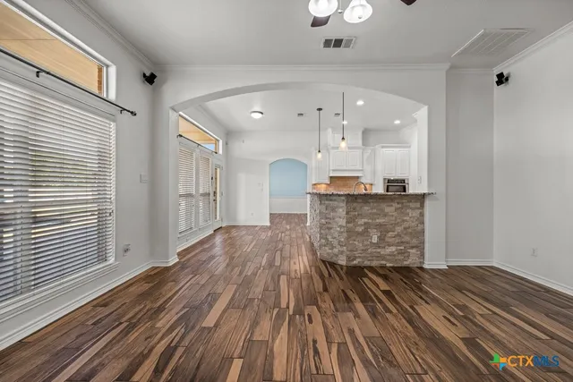 a view of kitchen and empty room with wooden floor