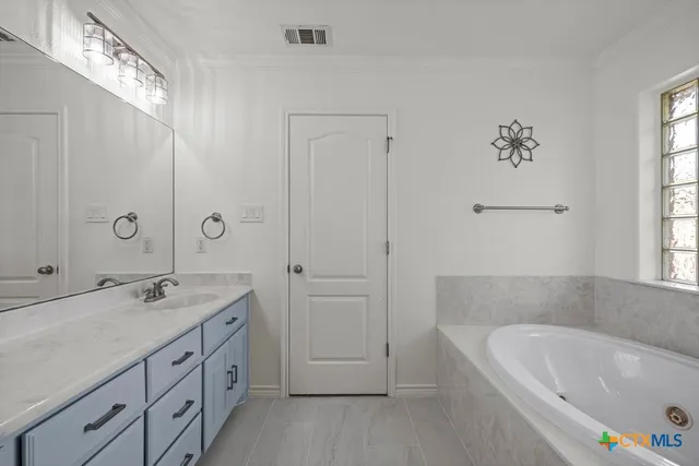 a bathroom with a tub a sink and mirror