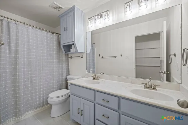a bathroom with a granite countertop sink a toilet and a mirror