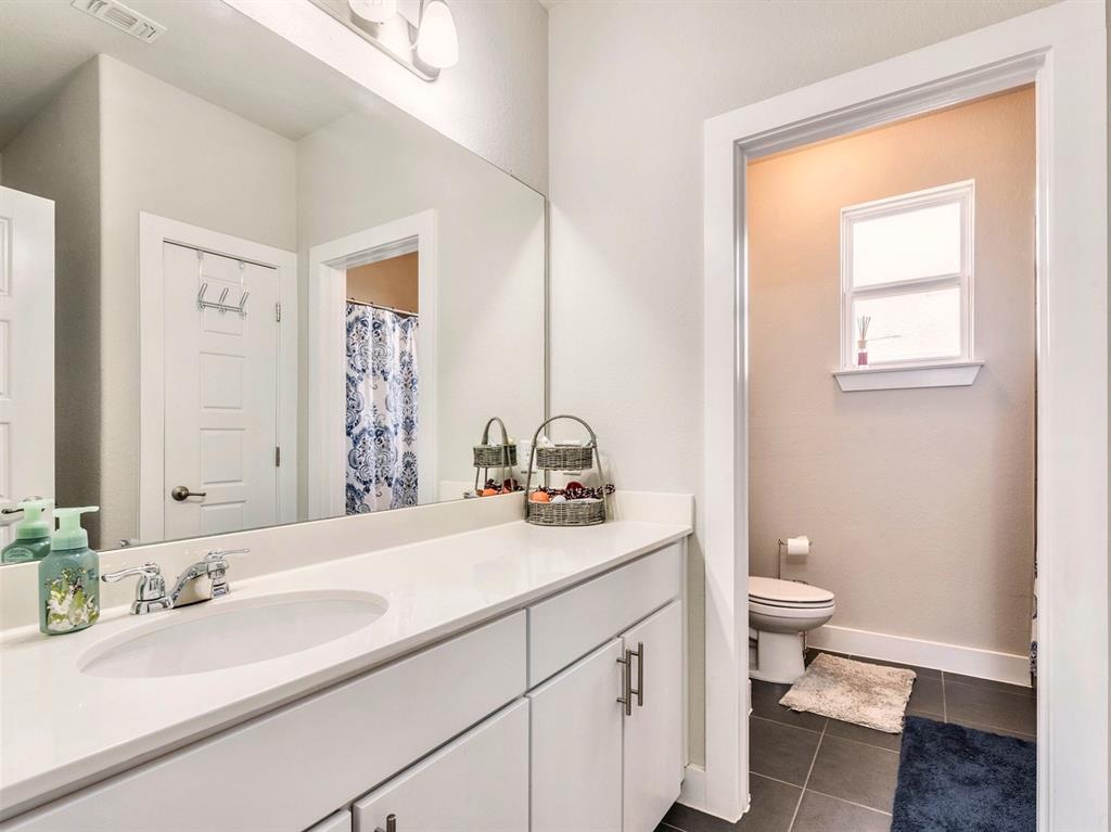 7001 Brick Slope Path Austin, TX 78744 - Photo 15 of 27 Bathroom featuring vanity, dark tile patterned floors, and curtained shower