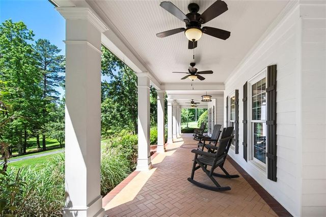 a large white kitchen with stainless steel appliances kitchen island granite countertop a table chairs sink and cabinets