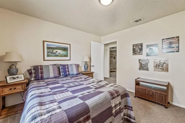 a spacious bedroom with a bed and a flat tv screen