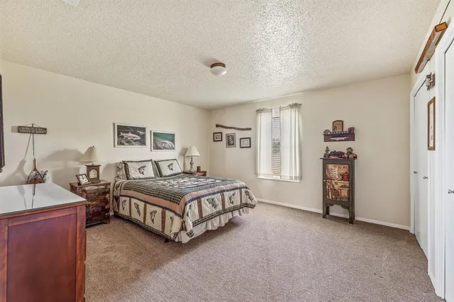 a spacious bedroom with a bed and a lamp on table