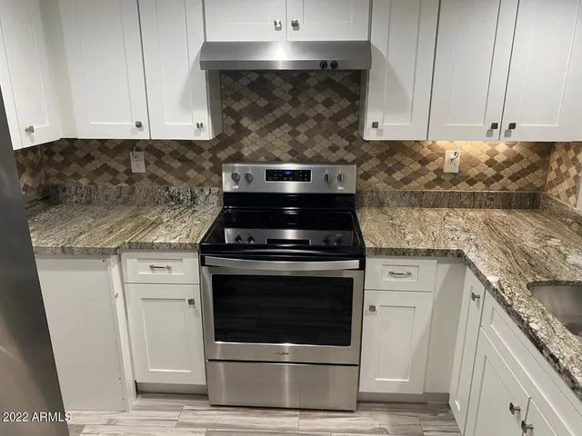a kitchen with granite countertop white cabinets and stainless steel appliances