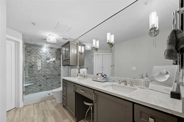a bathroom with a granite countertop sink a toilet a large mirror and shower
