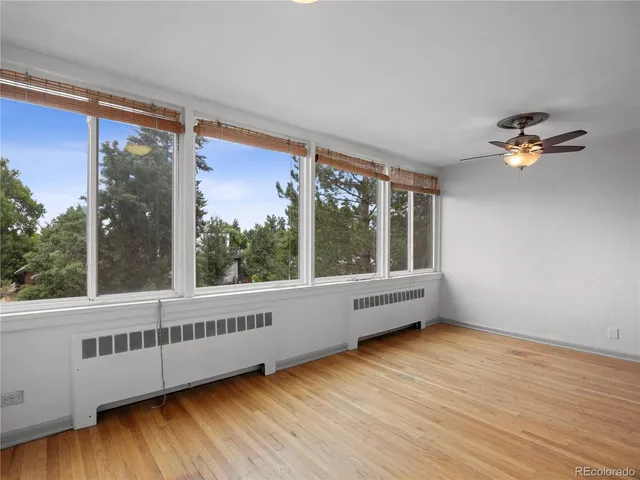 a view of an empty room with a window and wooden floor