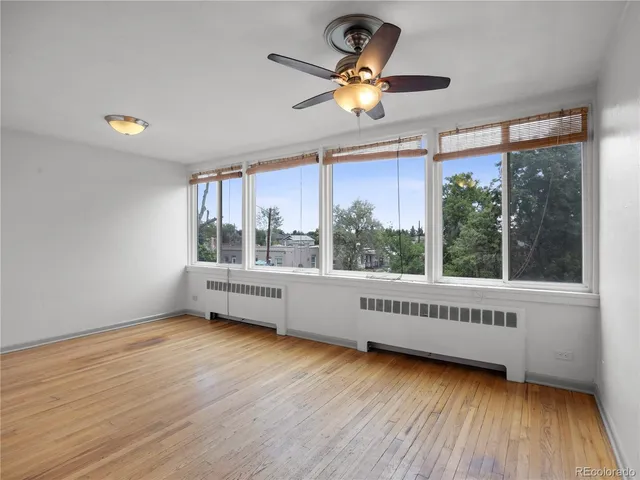 a view of an empty room with a window and wooden floor