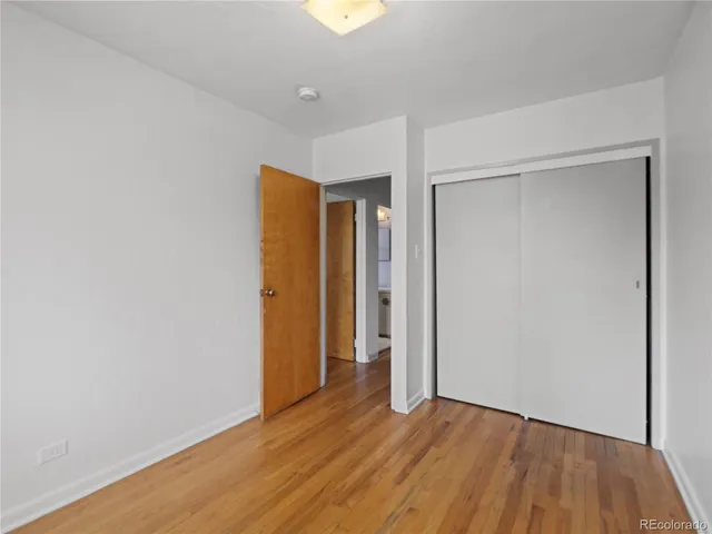 a view of an empty room with wooden floor and closet