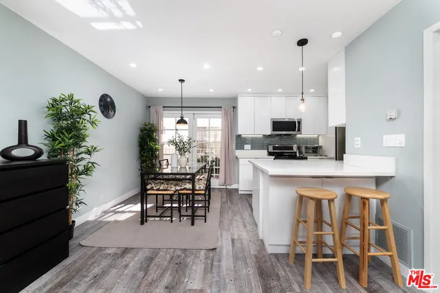 a kitchen with stainless steel appliances kitchen island granite countertop a table chairs and a refrigerator