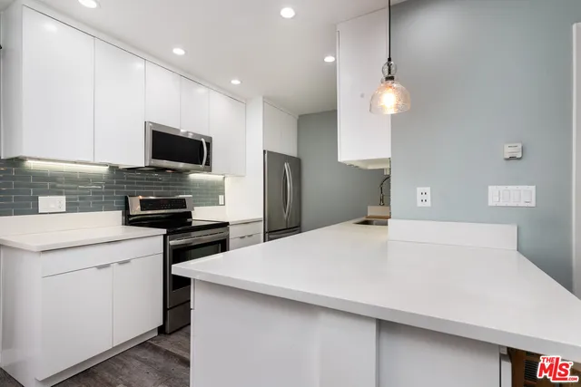 a kitchen with kitchen island a sink stainless steel appliances and cabinets