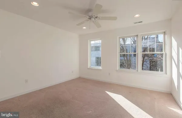 an empty room with chandelier fan and windows