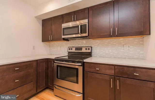 a kitchen with granite countertop cabinets stainless steel appliances and wooden floor