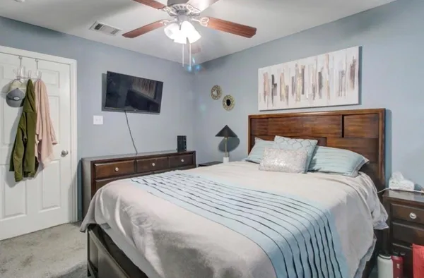 a bedroom with a bed and a flat tv screen on the dresser