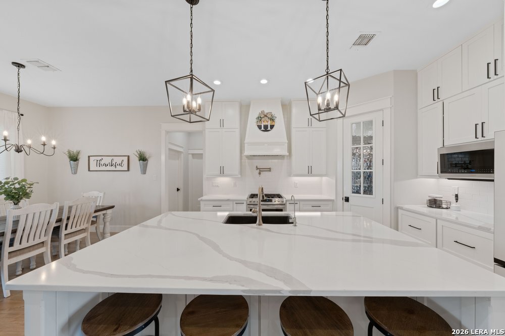 116 Park Heights Poth, TX 78147 - Photo 9 of 48 a kitchen with stainless steel appliances a table chairs and white cabinets
