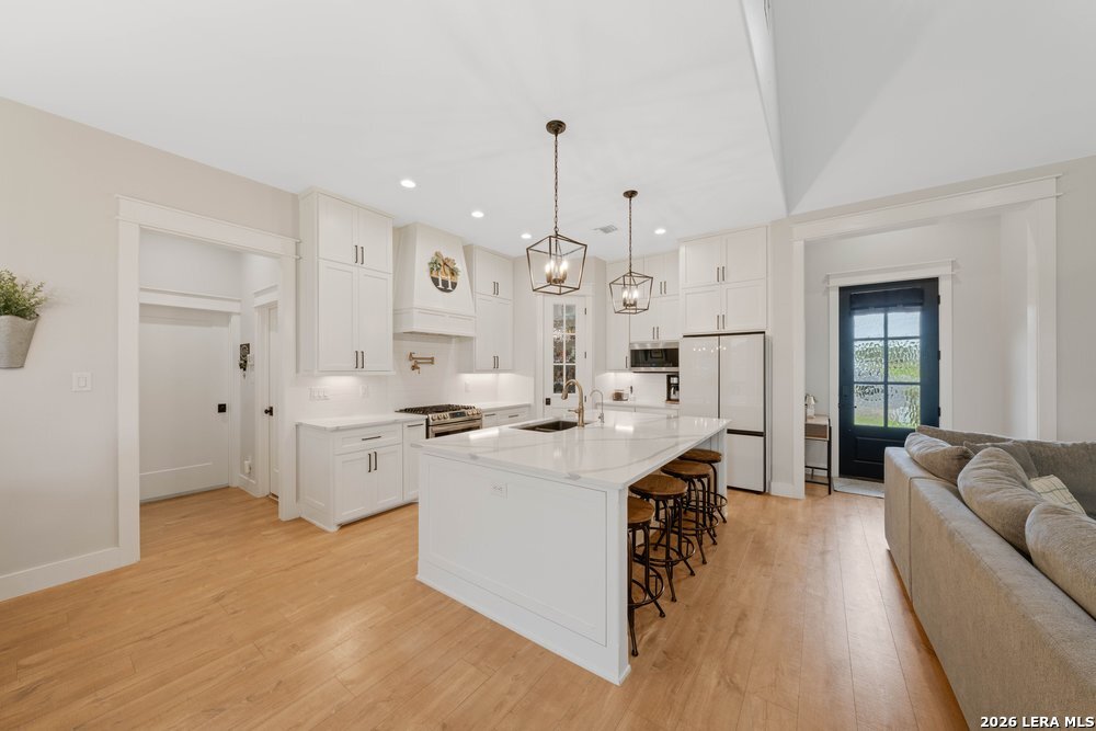 116 Park Heights Poth, TX 78147 - Photo 10 of 48 a large kitchen with stainless steel appliances kitchen island a stove a sink dishwasher and a dining table with wooden floor