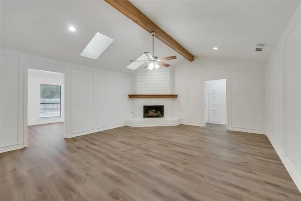 a view of an empty room with wooden floor and a fireplace