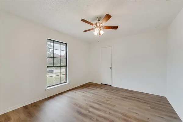 an empty room with wooden floor closet and windows