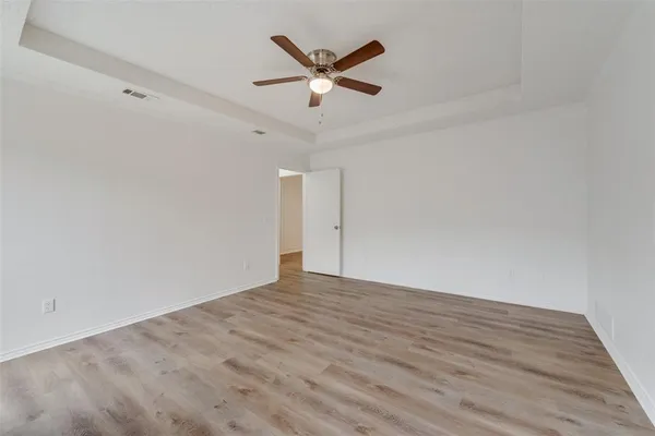 an empty room with wooden floor and ceiling fan