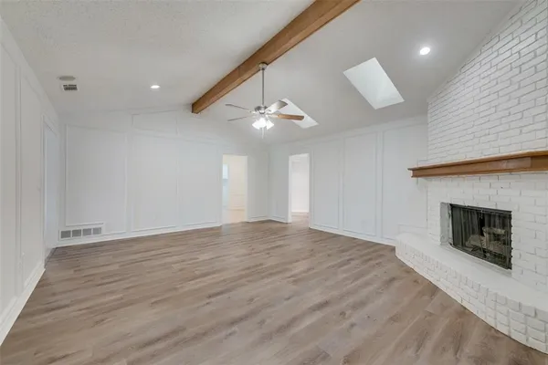 a view of an empty room with wooden floor fireplace and a window