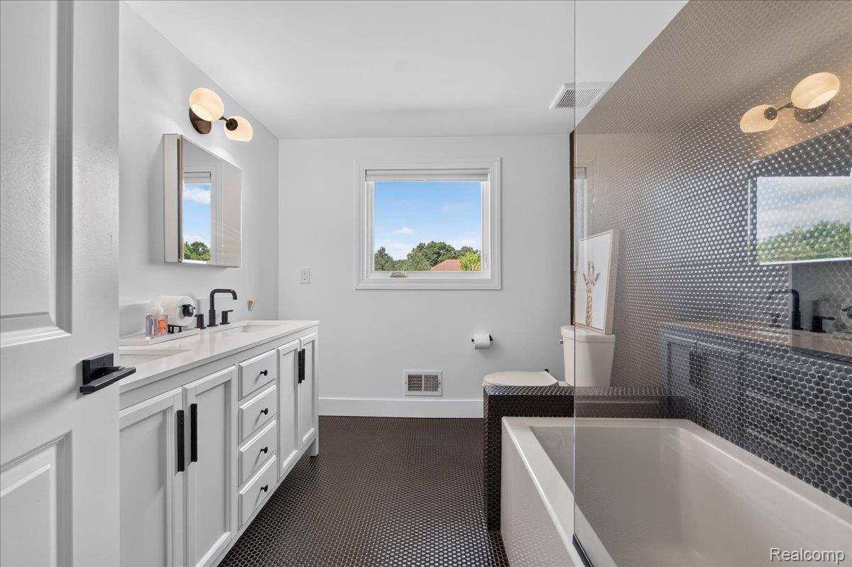 7330 West Gates Street Romeo, MI 48065 - Photo 39 of 73 White vanity with a solid surface countertop, matte black faucet, and pendant lighting