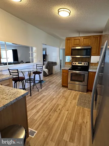 a living room with stainless steel appliances furniture a rug and a kitchen view