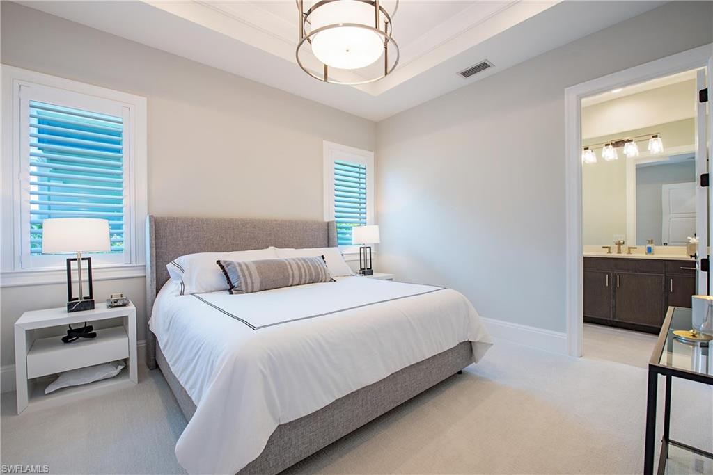 6830 Mangrove Avenue Naples, FL 34109 - Photo 18 of 28 a bedroom with a bed and a chandelier