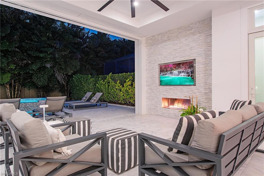 6830 Mangrove Avenue Naples, FL 34109 - Photo 7 of 28 a view of a patio with table and chairs potted plants with wooden floor and seating space