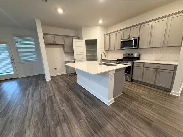 a kitchen with wooden floors and white stainless steel appliances