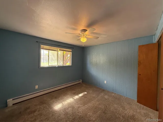 an empty room with windows and fan